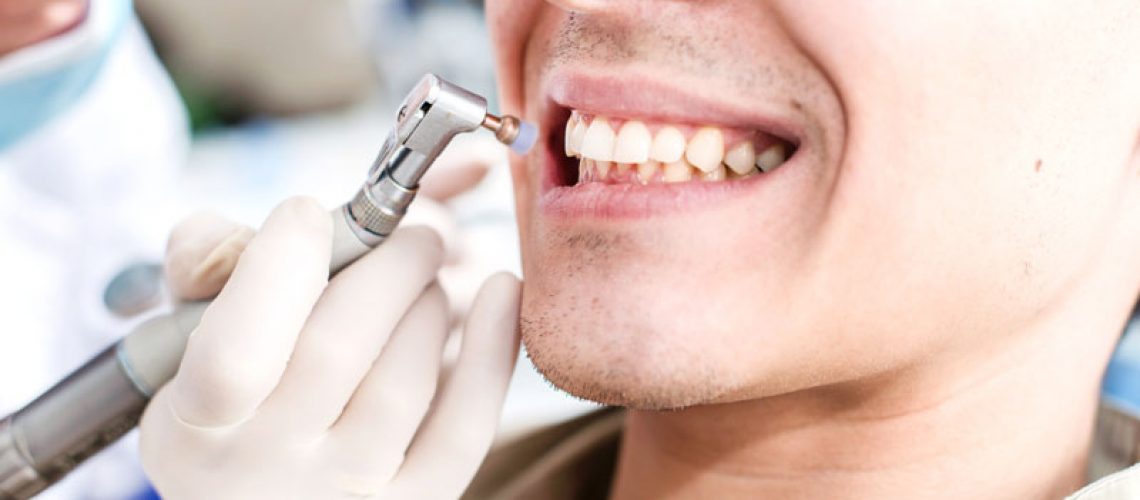 a picture of a patient smiling as a general practitioner gives him a tooth cleaning during his general dentistry appointment.